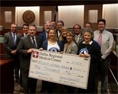 Dallas Regional Medical Center holding check for Mesquite Veterans Memorial