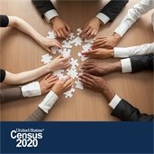 Photo of multicultural hands putting together a white puzzle on a brown table. At the bottom of the photo are the words United States Census 2020.