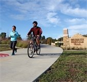 man rides bike and woman runs on trail