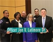 Family and police colleagues of retired Officer Jon V. Latimore. Holding a replica of street sign that says "Officer Jon V. Latimore Dr."
