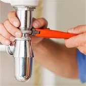 man fixing pipe under sink 