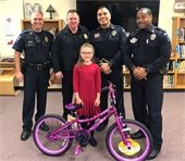 Four Mesquite police officers pictured with a young girl and a pink bike she donated to the Santa Cop toy drive