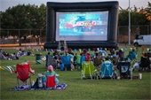people watching a movie outside on an inflatable screen 