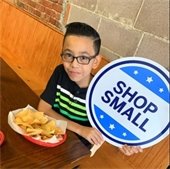 little boy hodling shop small sign