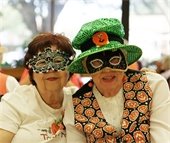 Two female senior residents posting together wearing masquerade masks 