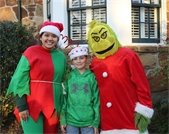 Young boy pictured with event volunteer wearing an elf costume and event volunteer wearing Grinch costume
