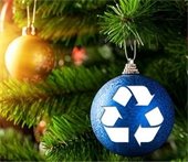 Christmas tree with a gold decorative bulb and a blue decorative bulb. The blue bulb has the universal symbol for recycling stamped on top in white