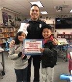 Officer Contreras posing holding books with two students