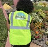woman picks up trash in clean city vest
