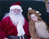 Young boy dressed as a reindeer posing with Santa