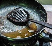 Leftover cooking grease in pan with used spatula on top