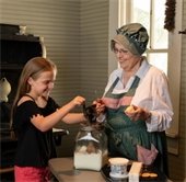 A volunteer dressed in pioneer clothing greets a visitor at Opal Lawrence Historical Park