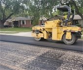 Yellow construction vehicle milling a residential road in Mesquite. 
