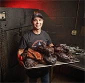 mesquite bbq worker holds up brisket